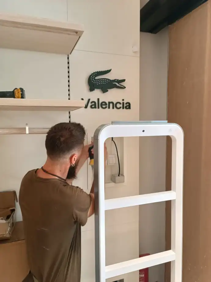 Instalación de alarmas Aingenia Trabajador de Aingenia colocando cámara de seguridad en tienda Lacoste